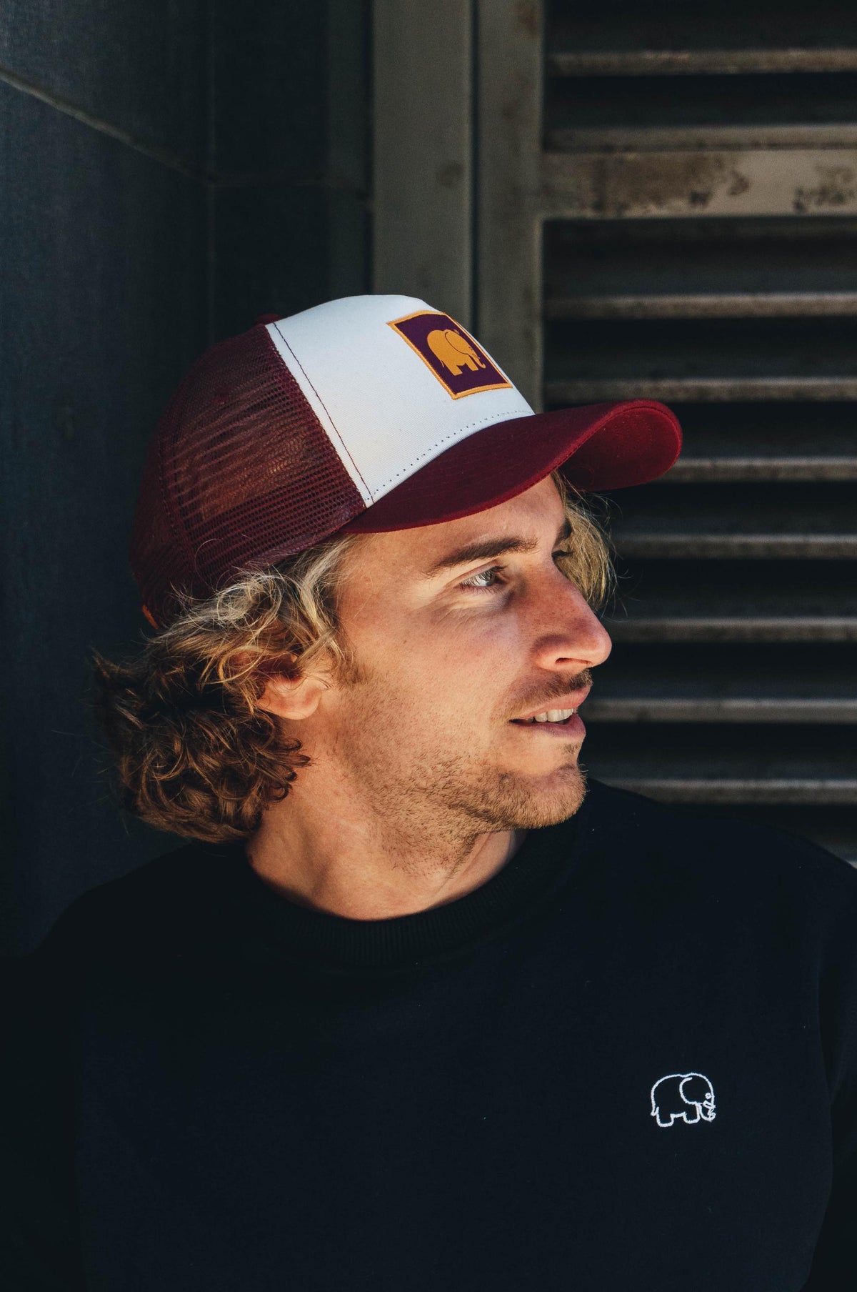 Personne portant une Classic Trucker Cap Burgundy, vue de côté avec une tenue décontractée | TP_IMAGE_TYPE=MODEL_FRONT
